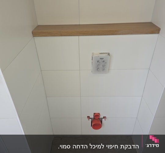 צנרת אדומה בקיר לבן עם מדף עץ